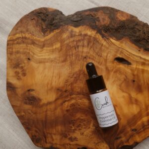 Peppermint essential oil in amber dropper bottle on a wooden board