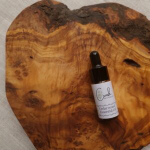 Cedarwood essential oil in amber dropper bottle on wooden board